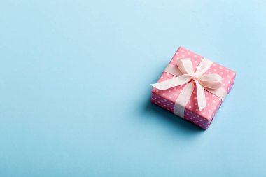 Noel 'i ya da diğer tatil hediyelerini renkli arka planda kurdeleyle renkli kağıda sardım. Şimdiki kutu, renkli tabloda hediye süslemesi, kopya alanı ile üst görünüm.