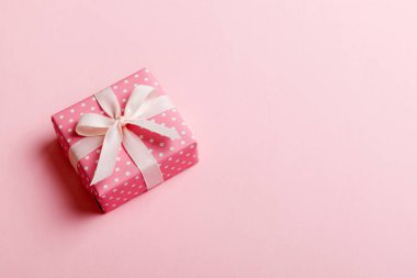 Noel 'i ya da diğer tatil hediyelerini renkli arka planda kurdeleyle renkli kağıda sardım. Şimdiki kutu, renkli tabloda hediye süslemesi, kopya alanı ile üst görünüm.