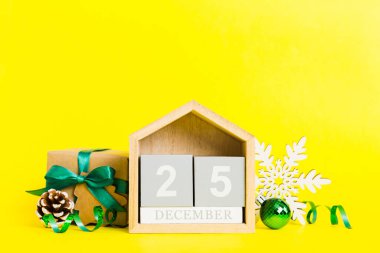 25 december. Christmas composition on colored background with a wooden calendar, with a gift box, toys, bauble copy space.