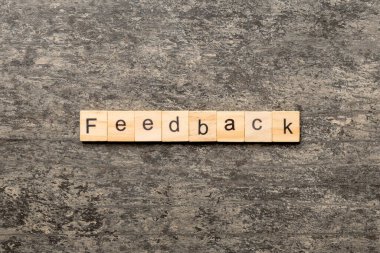 Tahta blokta yazan geri bildirim kelimesi. Deksing, konsept için çimento masadaki geri bildirim metni.