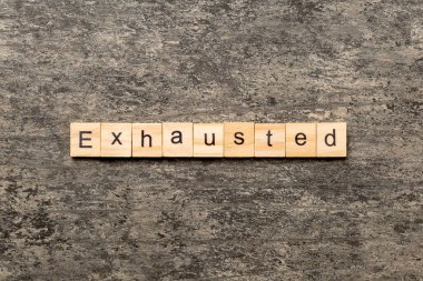 Tahta bloğa yazılmış tükenmiş bir kelime. Çimento masasında yorulmuş metin desing, konsept için.