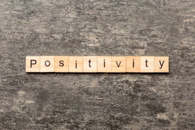 Tahta bloğa olumlu bir kelime yazılmış. Çimento sehpası üzerinde pozitif metin desing, konsept için.