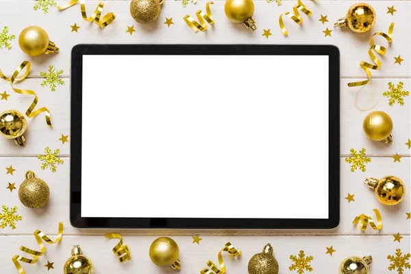 Noel alışverişi boş beyaz ekranlı tablet bilgisayardan yapılıyor. Renkli arka planda noel süsleme toplarıyla fotokopi alanı olan tablet. Kış tatillerinde satış geçmişi.