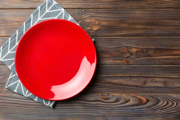 stock image Top view on colored background empty round red plate on tablecloth for food. Empty dish on napkin with space for your design.