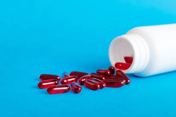 Red pills spilled around a pill bottle. Medicines and prescription pills flat lay background. Red medical capsules.