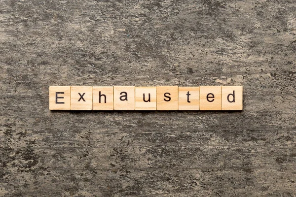 Tahta bloğa yazılmış tükenmiş bir kelime. Çimento masasında yorulmuş metin desing, konsept için.
