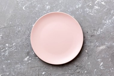 Çimento arka planındaki boş pembe tabağın üst görüntüsü. Tasarımın için boş boşluk.