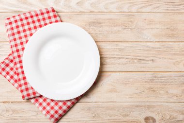 Renkli arka planda üst görünüm yiyecek için masa örtüsü üzerindeki boş yuvarlak beyaz tabak. Tasarımınız için boşluk olan peçeteye boş tabak.