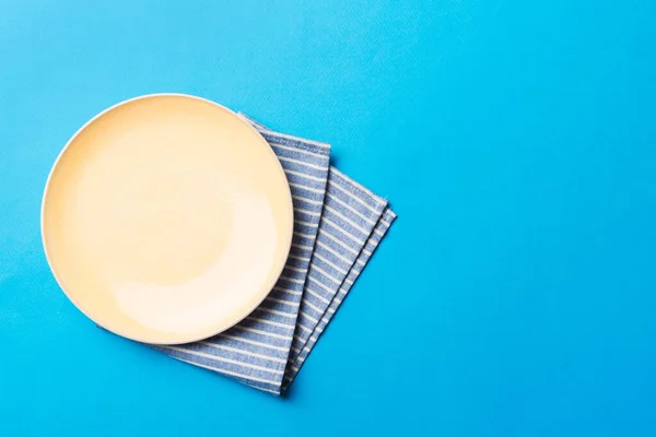 stock image Top view on colored background empty round yellow plate on tablecloth for food. Empty dish on napkin with space for your design.