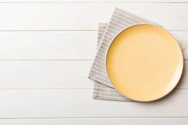 stock image Top view on colored background empty round yellow plate on tablecloth for food. Empty dish on napkin with space for your design.