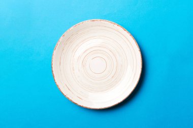Renkli arka plan görüntüsünün üst görüntüsü yiyecek için boş, yuvarlak bej bir tabak. Tasarımınız için alanı olan boş tabak.