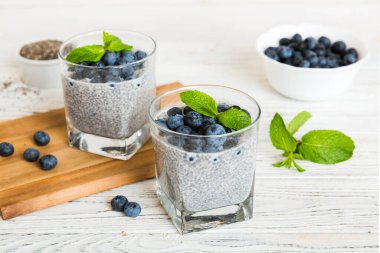 Sağlıklı kahvaltı ve chia tohumlu vanilyalı puding ve böğürtlenli masa arkası, vejetaryen gıda, diyet ve sağlık konsepti. Hindistan cevizi sütü ve yabanmersinli Chia pudingi..