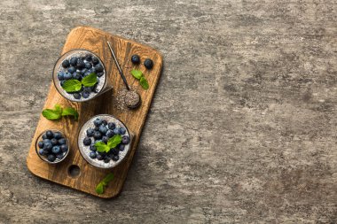 Sağlıklı kahvaltı ve chia tohumlu vanilyalı puding ve böğürtlenli masa arkası, vejetaryen gıda, diyet ve sağlık konsepti. Hindistan cevizi sütü ve yabanmersinli Chia pudingi..