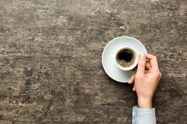 Renkli arka planda bir fincan kahve tutan minimalist stil bir kadın. Düz yerde, kapuçino bardağının üstünde. Metin için boş yer, kopyalama alanı. Kahve bağımlılığı. Üst manzara, düz uzanma.