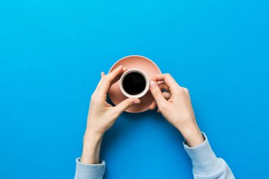 Renkli arka planda bir fincan kahve tutan minimalist stil bir kadın. Düz yerde, kapuçino bardağının üstünde. Metin için boş yer, kopyalama alanı. Kahve bağımlılığı. Üst manzara, düz uzanma.