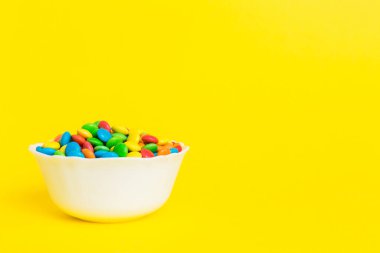 Renkli arka planda bir kasede çok renkli şekerler. Doğum günü ve tatil konsepti. Kopyalama alanı olan üst görünüm.