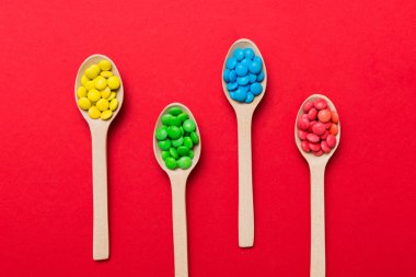 Renkli arka planda kaşık üzerinde renkli tatlı şekerler. Fotokopi alanı ile şekerleme dekoru üst görünümü.