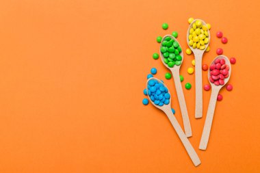 Renkli arka planda kaşık üzerinde renkli tatlı şekerler. Fotokopi alanı ile şekerleme dekoru üst görünümü.