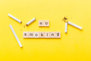 Sigara ve tahta bloklar, masa arkasında kırık sigara kum saati ile tütün günü yok, saat sağlığı konsepti. Sigarayı bırakma zamanı..