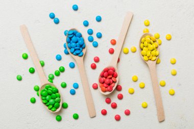 Renkli arka planda kaşık üzerinde renkli tatlı şekerler. Fotokopi alanı ile şekerleme dekoru üst görünümü.