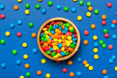 Renkli arka planda bir kasede çok renkli şekerler. Doğum günü ve tatil konsepti. Kopyalama alanı olan üst görünüm.