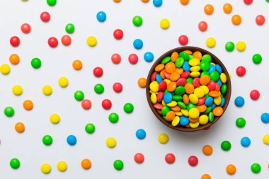 Renkli arka planda bir kasede çok renkli şekerler. Doğum günü ve tatil konsepti. Kopyalama alanı olan üst görünüm.