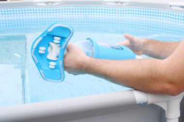 Adam havuz temizleyicisi ve havuzun bakımını yapıyor..