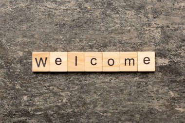 Ahşap blok üzerinde yazılı kelime hoş geldiniz. Hoş geldiniz metni masaya, kavram.