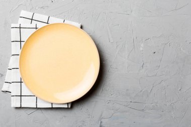 Renkli arka planda üst manzara. Yemek için masa örtüsü üzerinde boş yuvarlak sarı tabak. Tasarımınız için boşluk olan peçeteye boş tabak.