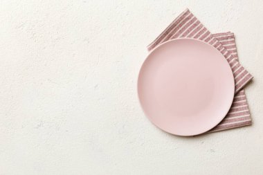 Renkli arka planda üst manzara. Yemek için masa örtüsü üzerine yuvarlak pembe tabak. Tasarımınız için boşluk olan peçeteye boş tabak.