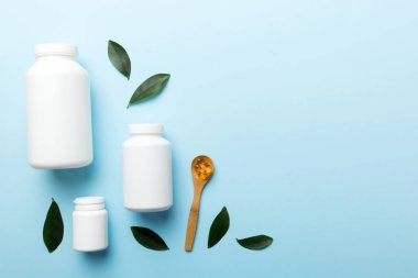 Omega-3 kapsülleri yeşil yapraklı arka planda beyaz bir şişede yatar. Balık yağı tabletleri. Biyolojik olarak aktif katkı maddeleri. Omega 6, Omega 9, A vitamini, E, D vitamini, D3 vitamini..