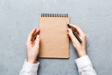 Defterine kalem yazan kadın eli. Ofis masasında çalışan bir kadın. Kalem ve çizim defterini tutan kadın. Model Konsepti.