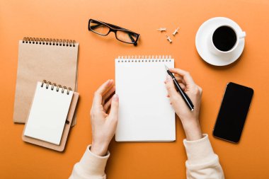 Not defterine kalem yazan ve kahve bardağını tutan kadın eli. Kahve masasında çalışan bir kadın..