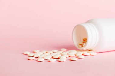 Medicine bottle and white pills spilled on a light background. Medicines and prescription pills flat lay background. White medical pills and tablets spilling out of a drug bottle.