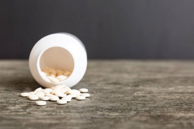 Medicine bottle and white pills spilled on a light background. Medicines and prescription pills flat lay background. White medical pills and tablets spilling out of a drug bottle.