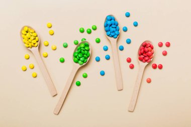 Renkli arka planda kaşık üzerinde renkli tatlı şekerler. Fotokopi alanı ile şekerleme dekoru üst görünümü.