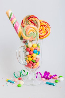 Masanın üzerinde açık arkaplanda renkli şekerler. Büyük kıvrımlı lolipoplar. Şekerci dükkanından leziz şekerlerle dolu yaratıcı bir kavanoz konsepti.