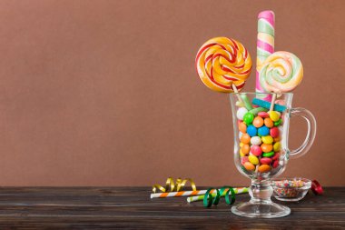 Masanın üzerinde açık arkaplanda renkli şekerler. Büyük kıvrımlı lolipoplar. Şekerci dükkanından leziz şekerlerle dolu yaratıcı bir kavanoz konsepti.