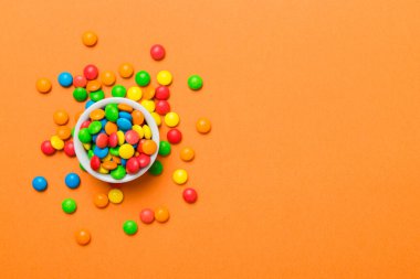 Renkli arka planda bir kasede çok renkli şekerler. Doğum günü ve tatil konsepti. Kopyalama alanı olan üst görünüm.