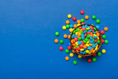 Renkli arka planda bir kasede çok renkli şekerler. Doğum günü ve tatil konsepti. Kopyalama alanı olan üst görünüm.