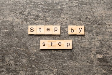 Ahşap bloğa adım adım yazılmış. Masada adım adım metin, konsept.