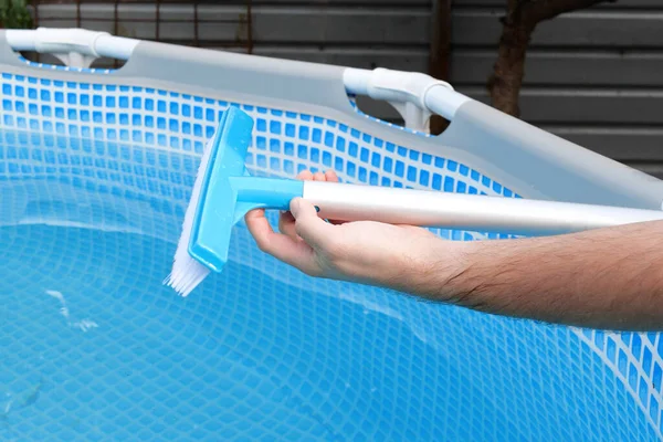 girl assembling swimming pool brush, cleaning pool with a special brush.