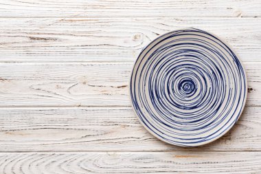 Ahşap zemindeki boş renkli tabağın üst görünümü. Tasarımın için boş boşluk.