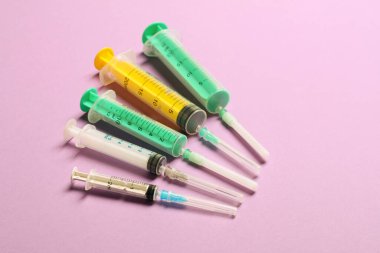 Mor arka planda şırıngalarla fotokopi alanının olduğu tıbbi şırıngaların üst görüntüsü. Enjeksiyon tedavisi kavramı.