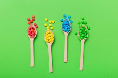 Renkli arka planda kaşık üzerinde renkli tatlı şekerler. Fotokopi alanı ile şekerleme dekoru üst görünümü.