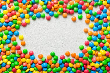 Renkli arka planda karışık renkli şeker koleksiyonu. Düz yerde, üst tarafta. Renkli çikolata kaplı şeker çerçevesi.