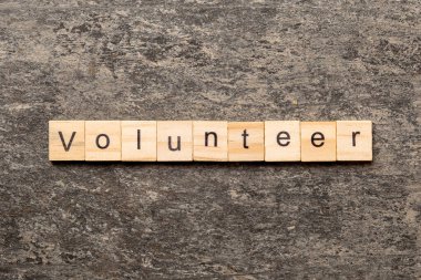 Tahta bloğa yazılmış gönüllü kelime. Gönüllü metin masa üzerinde, konsept.