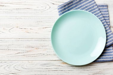 Renkli arkaplanda üst görünüm yiyecek için mavi tabak üzerinde boş. Tasarımınız için boşluk olan peçeteye boş tabak.
