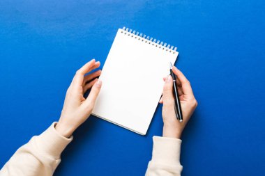 Defterine kalem yazan kadın eli. Ofis masasında çalışan bir kadın. Kalem ve çizim defterini tutan kadın. Model Konsepti.