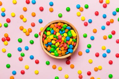 Renkli arka planda bir kasede çok renkli şekerler. Doğum günü ve tatil konsepti. Kopyalama alanı olan üst görünüm.